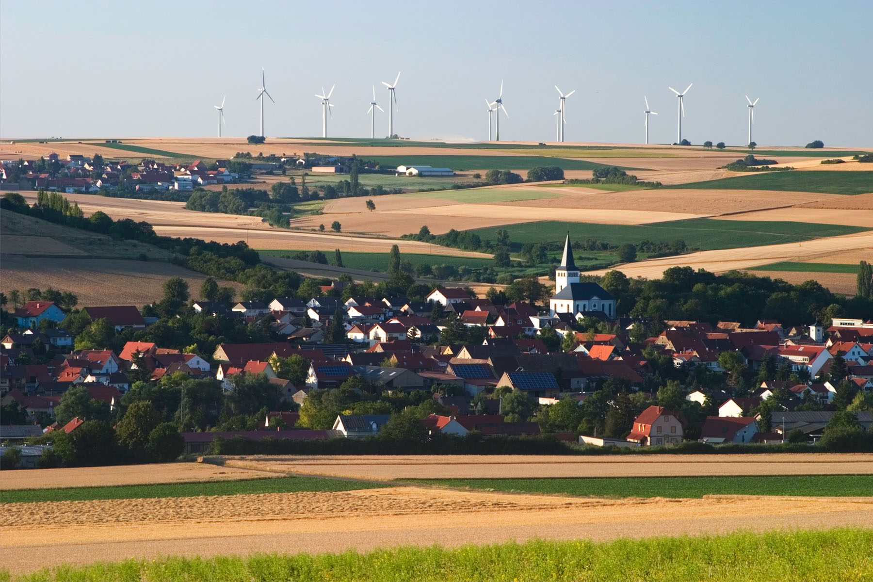 Rural landscape in southwestern Germany and wind turbines lining a hill.