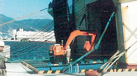 A self-propelled mini back-hoe loading a boat